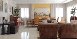 uma sala ampla e com ampla luminosidade, ombinação de cortina de tecido leve com persiana blackout.